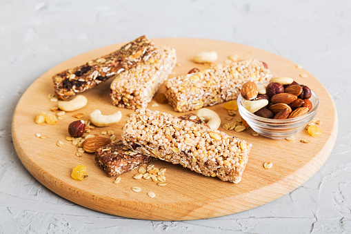 Various granola bars on table background. Cereal granola bars. Superfood breakfast bars with oats, nuts and berries, close up. Superfood concept.