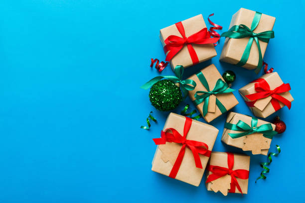 istock wrapped christmas or other holiday handmade present in paper with colored ribbon. Present box, decoration of gift on colourfull table, top view with copy space 1699897247