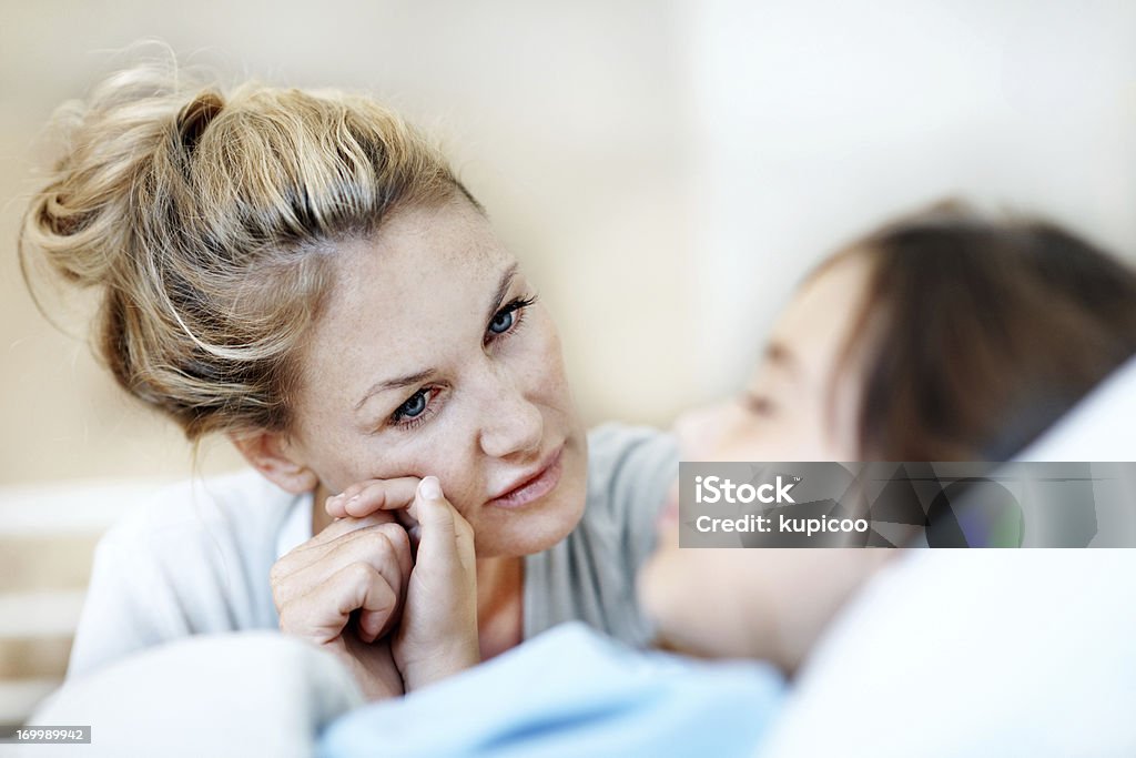Life is so delicate Worried mother holds her daughters hand while she lays in recovery after a operation Hospital Stock Photo
