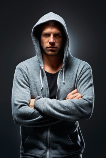 Portrait of trendy-looking man wearing a hooded sweatshirt with his arms folded