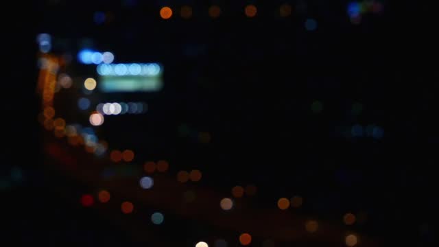 Footage video, defocused blurry motion colorful bokeh of city night light traffic, curved road, abstract dark background of cityscape, overlay effect