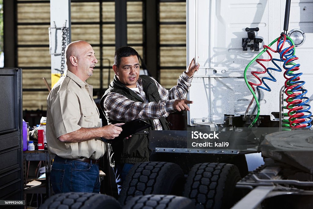 Men in garage with semi-truck Multi-ethnic men in service garage with semi-truck. Truck Stock Photo