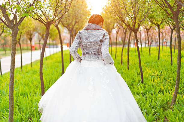 The back of the bride in sunlight of the woods