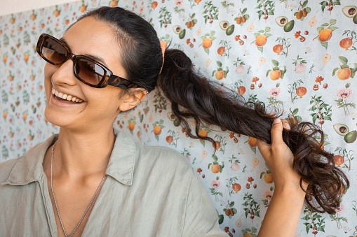 Portrait of a positive Latin woman with sunglasses  posing in front of colorful background