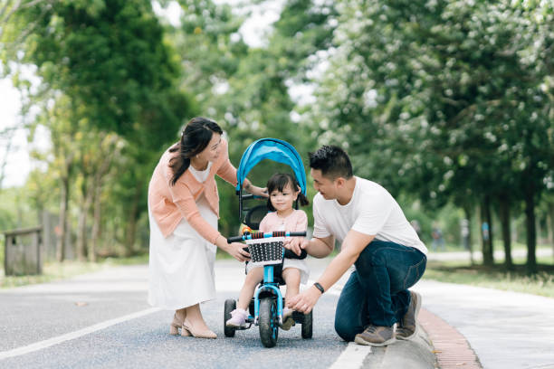 Young girl learning to ride a bicycle together with her parents