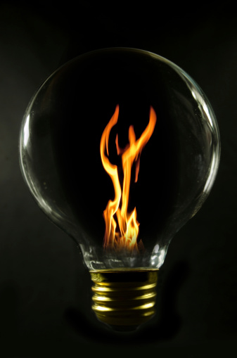 A orange flame inside a black light bulb with a black background. Black background 