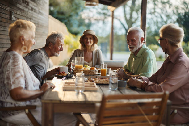 istock Group of happy seniors talking at picnic table on a patio. 1699963532