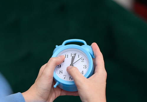 An alarm clock showing midnight held in the hands closeup