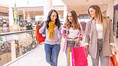 Cheerful beautiful girls are looking at bought Christmas gifts in a shopping mall.
