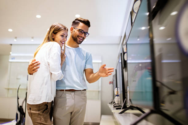 istock Young couple in consumer electronics store looking at latest digital devices, television. 1699987744