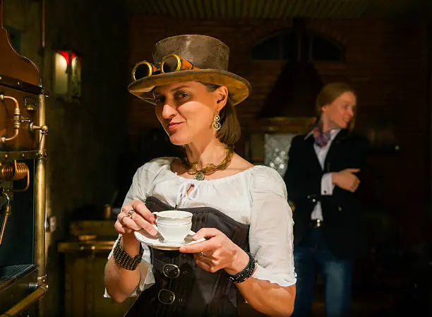 Young woman in steampunk stile make a coffee with coffee-macker machine