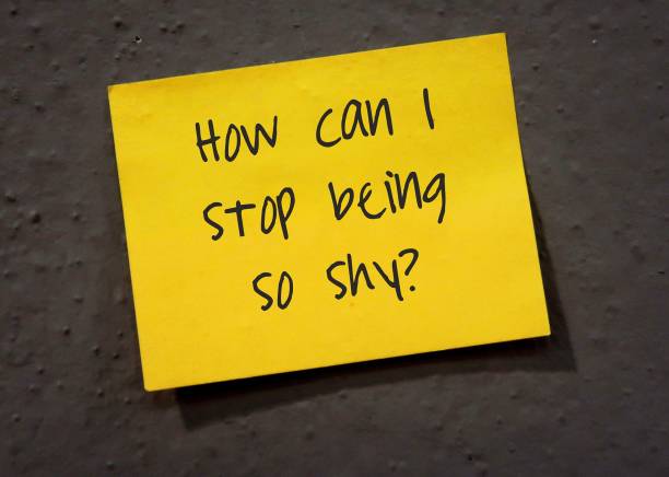 Yellow stick note on gray wall with handwritten - How Can I Stop Being So Shy? - concept of people struggling with shyness, overcome low self-esteem ,fear of judgment and rejection, to gain social opportunities and improve social skills. nota amarilla en la pared gris con escrito a mano - ¿cómo puedo dejar de ser tan tímido? - concepto de personas que luchan con la timidez, superan la baja autoestima, el miedo al juicio y al rechazo, para obtener oportunidades sociales y mejorar las hab