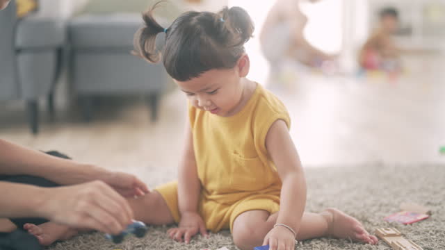 Asian mother and baby child girl learning to play with colorful wooden toy  in living room
