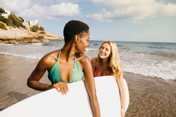 istock Cheerful friends carrying a surfboard at the beach 1699988792