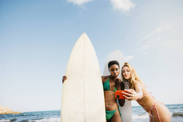 istock Female surfers taking a selfie on the beach 1699989312