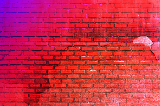 Red purple brown old brick wall. Toned colorful grunge background. Space. Design. Cracked, broken, crumbled. Color gradient. Rough backdrop.