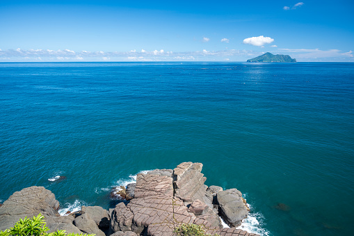 Blue sea and blue sky with changing white clouds. Small islands and rocks. Guishan Island(Turtle Island) is a volcanic island in the Pacific Ocean. Taiwan