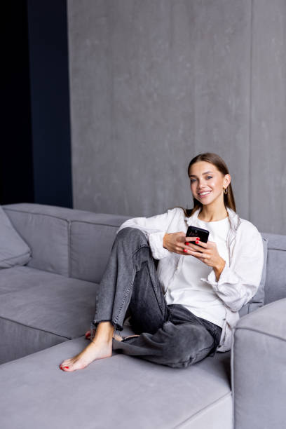 istock Happy woman relaxing on comfortable sofa using smartphone chatting in social networks, watching funny videos at home. 1700005822