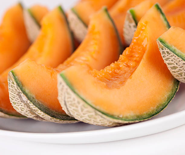 Sliced cantaloupe melons on a plate Portions of Cantaloupe on plate. Isolated on white background. Selective focus, shalow DOF. melon photos stock pictures, royalty-free photos & images