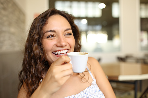 Happy woman holding coffee cup in a bar