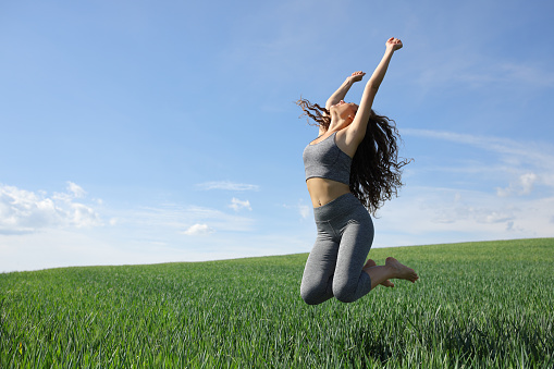 Happy sportswoman jumping in a field