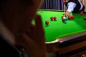 Snooker player while aiming to white ball shoot to hit the Snooker ball in game on snooker table in front of the competitors