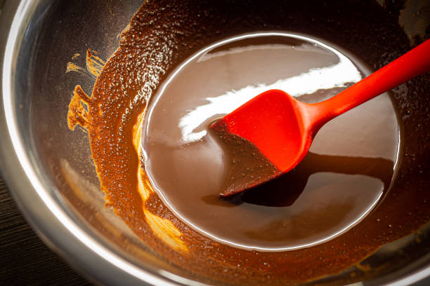 istock Woman cooking tasty melted chocolate on table in kitchen. 1700027915