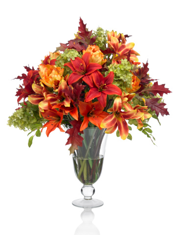 A large fall lily bouquet with autumn leaves in a footed glass vase. This image has an embedded path which may be used to delete the reflection if desired. Photographed on a bright white background. Extremely high quality faux flowers.