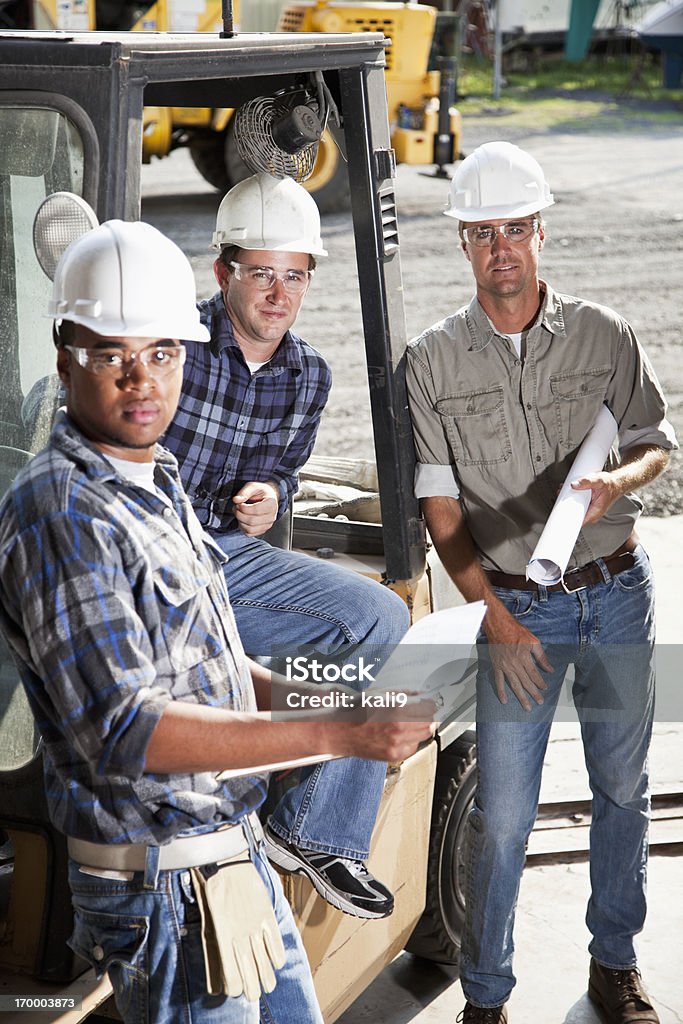 Multirracial los trabajadores con carretilla elevadora - Foto de stock de Casco Duro libre de derechos