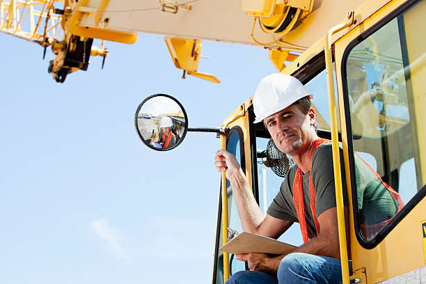 Crane operator Young man operating a crane at manufacturing facility. crane machinery photos stock pictures, royalty-free photos & images