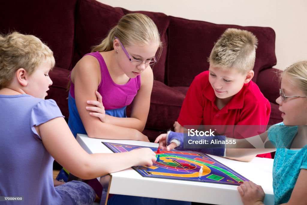 Grupo de niños jugar juego de mesa en la sala de estar - Foto de stock de Brazo fracturado libre de derechos