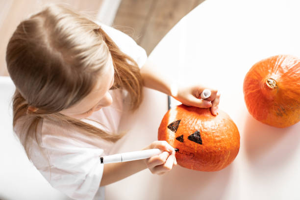 istock Girl draws on a pumpkin 1700055073