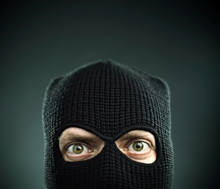 Man with a balaclava looking at camera. Black background.