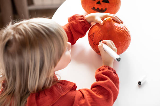 istock Girl draws on a pumpkin 1700057446