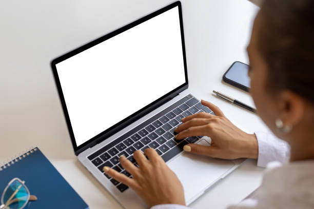 istock Woman using and typing on laptop with blank white desktop screen 1700057455
