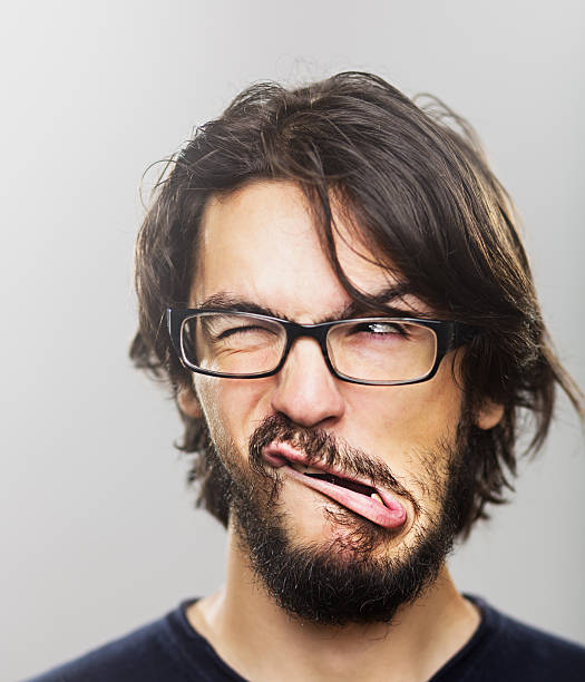 Young man grimacing Portrait of a young man with a beard winking and making a face. grimacing stock pictures, royalty-free photos & images