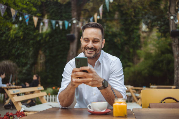 istock Happy Man Sending a Message With His Phone in Outdoors Cafe 1700062282