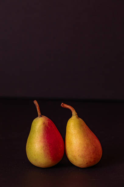 istock Two yellow autumn pears on the black background 1700064725