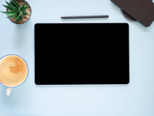 istock Digital tablet pc with empty black screen and pen, coffee cup, cactus on blue workplace. 1700076294