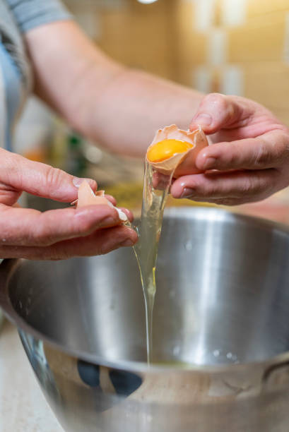 istock A woman breaks eggs in a bowl in the kitchen. cooking. 1700087942