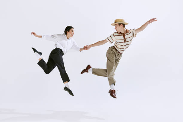 heureux et attrayant jeune homme et femme dans des vêtements vintage élégants dansant lindy hop isolé sur fond de studio blanc - country rock photos et images de collection