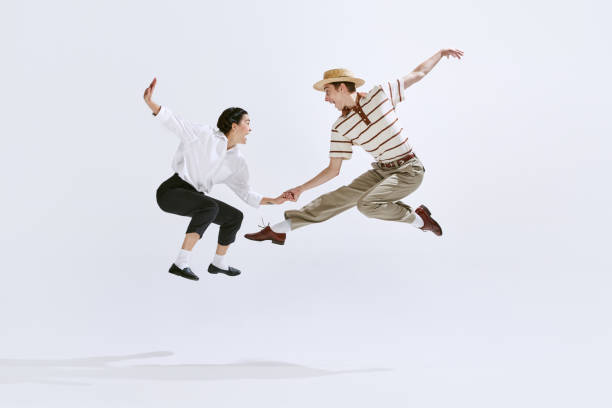 heureux et attrayant jeune homme et femme dans des vêtements vintage élégants dansant lindy hop isolé sur fond de studio blanc - country rock photos et images de collection