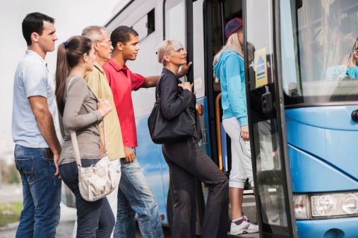 Large group of people boarding a bus.   