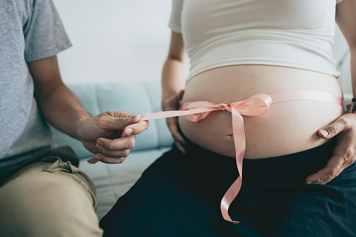 In a close-up shot, the father is untying the ribbon on the mother's belly, symbolizing the deep love of parents, their sense of responsibility, and the emotional connection within the family.