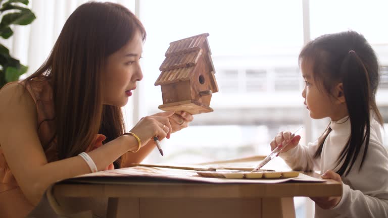 Little Girls Painting At The Model House With Her Mother