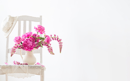 vintage bouquet of pink flowers in jug on white background