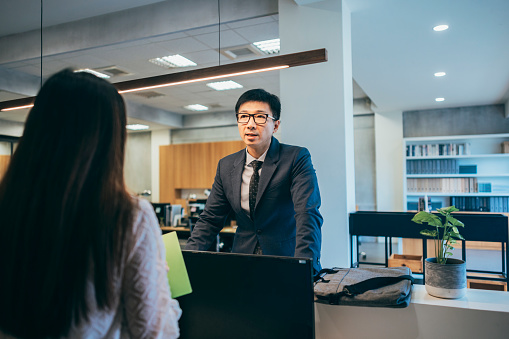 From the perspective behind the front desk staff, the front desk service personnel are attending to the needs of the visitors, verifying their information and business matters, showcasing the smooth operation of the front desk work.