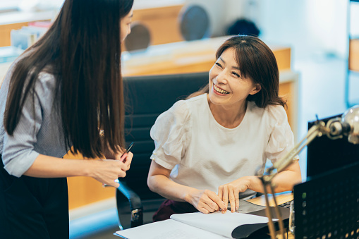 A young female employee is engaged in a conversation with her supervisor, seeking clarification and guidance on work-related matters. Their discussion reflects a proactive approach to problem-solving and a positive working relationship within the organization.