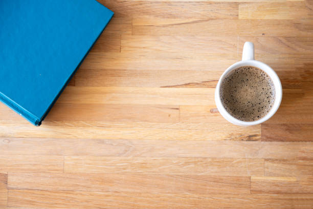 istock White cup of coffee on wooden background  with book 1700110928