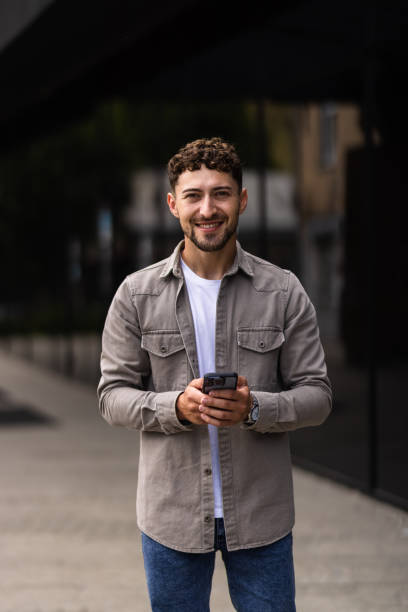 istock Confident young man using cell phone and drinking coffee in the city 1700123278